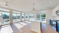 Located along Peachtree Road in the vibrant Brookhaven neighborhood of Atlanta, this modern single-floor residence showcases a clean, contemporary design with thoughtful finishes throughout. The open-concept living and kitchen area is a standout feature, anchored by a large central island with white quartz countertops and striking two-tone cabinetry — crisp white uppers paired with bold navy lowers — accented by gold hardware. Stainless steel appliances, including a gas range and built-in microwave, complete the well-appointed kitchen. A classic white subway tile backsplash adds a timeless touch. Floor-to-ceiling windows in the living area flood the space with natural light and offer panoramic views of the surrounding Brookhaven streetscape. Light-toned hardwood flooring runs throughout the main living areas, creating a warm and cohesive feel. The bedrooms are carpeted for comfort and feature ceiling fans and generous windows. A spacious walk-in closet with wire shelving provides ample storage. The bathroom is finished with large-format white tile surrounding the tub-shower combination and oil-rubbed bronze fixtures. A dedicated laundry area with a full-size washer and dryer adds everyday convenience. A bright, clean hallway with recessed lighting connects all areas of the home seamlessly.
