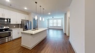 Located at 2007 Knoll Top Ln in Franklin, Tennessee, this single-floor residence offers a thoughtfully designed open-concept layout that blends modern finishes with comfortable living. The kitchen serves as a central highlight, showcasing white shaker cabinetry, a grey subway tile backsplash, quartz countertops, and a large island with a stainless steel sink and pendant lighting above. Stainless steel appliances, including a refrigerator with ice and water dispenser, a range, and a built-in microwave, complete the space. Warm hardwood-style flooring flows seamlessly throughout the entire residence, adding continuity and warmth. The open living area is bathed in natural light from large windows and features a ceiling fan, creating a bright and airy atmosphere. The bedrooms are well-proportioned, each with ceiling fans and windows fitted with blinds. The primary bathroom features a wide quartz vanity, a framed mirror, brushed nickel fixtures, a walk-in closet, and a glass-enclosed shower. A secondary bathroom includes a full soaking tub with a shower and curved rod. Clean white walls and recessed lighting throughout contribute to the residence's crisp, contemporary aesthetic.