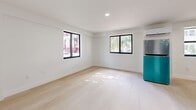 Located at 345 SW Fifth Ave in Miami's vibrant Brickell neighborhood, this single-floor unit offers an efficient and thoughtfully designed layout. The open main living area is bright and clean, featuring light wood flooring that runs throughout the space and crisp white walls that enhance the sense of openness. Two black-framed windows allow natural light to fill the room while providing views of the surrounding streetscape, and a wall-mounted mini-split A/C unit ensures climate comfort year-round. A stainless steel refrigerator with teal accents anchors the transition between the living and kitchen areas. The kitchen is well-appointed with white shaker cabinetry, light countertops, a stainless steel sink, a full stainless steel range with oven, and an over-the-range microwave — providing a complete cooking setup within a compact footprint. A closet with double doors offers convenient storage within the main living space. The bathroom continues the clean, modern aesthetic with light wood-look flooring, a white vanity with brushed nickel hardware, and a full walk-in shower with white tile surround and brushed nickel fixtures. The overall design is minimal, functional, and well-suited for urban living in the heart of Miami.