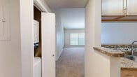 Located at 2821 Carlisle Street in Dallas, TX, this one-bedroom, one-bathroom unit offers a well-planned layout across a single floor. The living area is a standout feature, boasting soaring vaulted ceilings and a ceiling fan that enhance the sense of openness and airflow. Soft carpeting runs throughout the living and bedroom areas, while natural light filters in through blinded windows. The kitchen is efficiently designed with light wood cabinetry, granite-style countertops, a mosaic tile backsplash, hardwood-style flooring, and black appliances including a full-size refrigerator, range, and dishwasher. A hallway leads to the bedroom, which is comfortably sized and includes its own ceiling fan, a window for natural light, and direct access to both a closet and the bathroom. The bathroom features tile flooring, a tub-shower combination with full tile surround, and warm wood vanity cabinetry with granite-style countertops. A dedicated closet off the hallway houses a stacked in-unit washer and dryer, adding everyday convenience. The textured ceilings throughout contribute to the overall character of the space, making this a functional and well-appointed residence in Dallas.