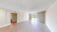 Located at 5903 Northwest 57th Court in Tamarac, Florida, this single-story home offers four bedrooms and two bathrooms across a well-organized floor plan. Light wood-style flooring flows consistently throughout the home, complemented by neutral-toned walls and textured ceilings that lend a clean, cohesive aesthetic.

The spacious living room is a standout feature, filled with natural light thanks to a large sliding glass door that opens to an outdoor view of lush greenery, creating a bright and open atmosphere. The updated kitchen is thoughtfully designed with white shaker cabinetry, sleek quartz-style countertops, a tile mosaic backsplash, and stainless steel appliances including a range, microwave, dishwasher, and refrigerator. A louvered pantry door adds a practical storage element.

The primary bedroom is generously sized, offering ample space for furnishings. Additional bedrooms are well-proportioned, with at least one featuring a built-in closet with a hanging rod. The bathrooms are finished in a clean, modern style — one showcasing a white vanity with a large mirror and a full bathtub and shower surround. A hallway connects the bedroom wing, providing a logical and efficient flow throughout the home. A dedicated closet offers additional storage capacity.