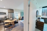 Located in Jamaica, NY, this thoughtfully designed two-bedroom, two-bathroom residence offers a smart and efficient single-level layout. The open-plan living, dining, and kitchen area serves as the heart of the home, anchored by large floor-to-ceiling windows that flood the space with natural light and frame views of the surrounding urban landscape. Light-toned hardwood flooring runs throughout, lending warmth and continuity to the space.

The kitchen is outfitted with high-gloss upper cabinetry, warm wood lower cabinets, white quartz countertops, and stainless steel appliances including a dishwasher and gas range — a clean, modern aesthetic built for everyday functionality. The adjacent dining area comfortably accommodates a round table, seamlessly connecting to the living room.

The primary bedroom features oversized windows with urban views, providing an airy and well-lit retreat. The second bedroom is cozy and well-proportioned, complete with a closet. Both bathrooms are finished in crisp white with modern floating vanities, mirrored medicine cabinets, and grey tile flooring — one featuring a soaking tub. Two closets and an in-unit laundry room round out the practical amenities of this well-appointed residence.