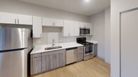 This contemporary 720 square foot apartment in Saint Paul, MN offers a blend of modern amenities and industrial design elements. The open floor plan maximizes the use of space, creating a seamless flow between living areas. Exposed ductwork along the ceiling adds an urban loft aesthetic, while large windows in multiple rooms flood the space with natural light and provide views of the surrounding neighborhood.

The kitchen is a standout feature, boasting sleek white upper cabinets contrasted with wood-grain lower cabinets. Stainless steel appliances, including a refrigerator, dishwasher, and range, complement the modern design. A quartz countertop and undermount sink complete the chef-friendly space.

The bathroom features a clean, white design with a shower/tub combination and modern fixtures. Carpet in the bedroom and living areas adds warmth, while the kitchen boasts durable hardwood flooring. A walk-in closet offers ample storage space.

The apartment's neutral color palette and minimalist design create a versatile canvas for various decorating styles. With its thoughtful layout and contemporary finishes, this apartment offers a comfortable and stylish urban living experience.
