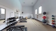 Located at 8504 82nd St SW in Tacoma, Washington, this single-floor fitness facility is purpose-built to support a comprehensive range of training activities. The space features impressively high ceilings that create an open, airy atmosphere, allowing for unrestricted movement and a sense of spaciousness throughout the workout area. The walls are finished in a clean, neutral white, and the flooring consists of a durable carpet tile surface with rubber mat stations positioned at key training areas.

Along the left wall, a full rack of dumbbells spans a wide range of weights, accompanied by multiple adjustable weight benches ideal for strength training. Large mirrors are mounted nearby, allowing athletes to monitor their form during lifts. Wall-mounted fans provide ventilation throughout the space.

The central floor area offers open room for functional movement, agility ladder drills, and floor-based exercises. A multi-station cable machine anchors the far end of the room, providing a versatile option for resistance training. To the right, resistance bands, exercise charts, and a collection of stability balls round out the facility's equipment offerings.

Natural light filters in through high windows along the right wall, enhancing the bright and motivating training environment. This facility is well-suited for personal training, athletic conditioning, and general fitness use.