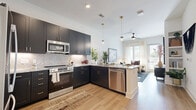 Located at 1425 Gallatin Pike N in Nashville, TN, this well-appointed one-bedroom, one-bathroom residence offers a thoughtfully designed layout that maximizes every square foot. The open-concept kitchen and living area serves as the heart of the home, where dark navy shaker-style cabinetry with gold hardware contrasts beautifully against light marble countertops and a herringbone tile backsplash. Stainless steel appliances, including a French door refrigerator, electric range, microwave, and dishwasher, complete the kitchen. Warm hardwood-style flooring flows throughout, complementing the bright, neutral palette. The living room benefits from large windows with sheer curtains that invite abundant natural light, and a glass door opens to an outdoor area, enhancing the sense of openness. The bedroom is a serene retreat with generous windows and its own access door, while the walk-in closet features multi-tiered wire shelving for ample storage. The bathroom offers a sleek, elongated vanity with dark cabinetry, marble countertops, and large-format light tile flooring. Gold accent fixtures tie the design together throughout the space, creating a cohesive modern aesthetic.