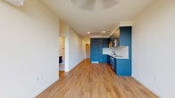 Located at 1703 Main St in Washougal, WA, this modern two-bedroom, one-bathroom unit is thoughtfully designed with contemporary finishes throughout. Light oak luxury vinyl plank flooring runs continuously across the entire floor plan, creating a clean, cohesive aesthetic.

The open-concept living area flows directly into the kitchen, which serves as a striking focal point with bold navy-blue cabinetry, warm wood open shelving, white tile backsplash, quartz countertops, and stainless steel appliances including a built-in oven, cooktop, and microwave. A ceiling fan with recessed lighting completes the living space.

Both bedrooms benefit from large, floor-to-ceiling black-framed windows that flood the rooms with natural light and offer expansive views of the surrounding wooded hillside and open sky. Each room includes a wall-mounted mini-split system for individual climate control.

The bathroom features a navy vanity with a vessel sink, matte black fixtures, a classic white subway-tiled tub/shower combo, and charming penny-tile flooring that adds texture and character.

A dedicated in-unit stacked washer and dryer closet provides added convenience. This well-appointed unit combines modern design with functional living in a scenic Washougal setting.