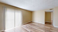 Located at 411 Tinker Diagonal St in Oklahoma City, Oklahoma, this single-floor, one-bedroom, two-bathroom residence offers a functional and straightforward layout across a compact but efficient footprint. The living room serves as the heart of the home, featuring light wood-style laminate flooring, warm neutral-toned walls, a textured popcorn ceiling, and a full-width sliding glass door dressed with vertical blinds that invite abundant natural light into the space. The bedroom continues the same light laminate flooring and neutral palette, with a window providing additional natural light and a dedicated closet with a built-in shelf for storage. Transitioning through the hallways, the flooring shifts to light ceramic tile, connecting the living areas to the two bathrooms. The bathrooms feature tile-surround tub and shower combinations with classic cream-toned wall tiles. Dark panel interior doors provide a contrasting accent throughout the home. The overall ambiance is clean, bright, and practical, offering a comfortable living environment well-suited for everyday use in the Oklahoma City area.