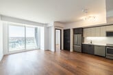 This thoughtfully designed one-bedroom, one-bathroom unit offers a clean, modern aesthetic throughout its efficiently organized single-floor layout. Warm-toned hardwood flooring flows consistently across all living areas, anchoring the bright, contemporary interior.

The open living area is highlighted by large floor-to-ceiling sliding glass doors that invite abundant natural light and offer urban views of the surrounding cityscape. The crisp white walls and clean lines create an airy, minimalist ambiance throughout.

The kitchen is well-appointed with a full suite of stainless steel appliances, including a French-door refrigerator, gas range, built-in microwave, and dishwasher. Two-tone cabinetry — combining dark wood lower cabinets with light upper cabinets — frames a white countertop with a modern undermount sink, all set against a clean white backsplash.

The bedroom is a calm, light-filled retreat, featuring hardwood floors and a generous window with urban views, providing a bright and comfortable space.

The bathroom is a standout feature, finished in elegant marble-effect tile covering both the floor and walls. It includes a walk-in shower with a ceiling-mounted rainfall showerhead, matte black fixtures, a vessel sink atop a white vanity, and contemporary dark wood accents — delivering a spa-like atmosphere with refined, high-end finishes.