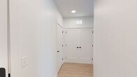 This well-appointed 2-bedroom, 2-bathroom unit at 100 Chestnut St in Ashland, MA offers a thoughtfully designed single-floor layout with modern finishes throughout. The open-concept kitchen and living area serves as the heart of the home, featuring a large quartz-topped island with an undermount sink, light wood cabinetry, stainless steel appliances including a refrigerator, range, and microwave, and a classic white subway tile backsplash accented by stylish pendant lighting. Light hardwood-style flooring flows through the main living areas. The living room opens directly to a private balcony through sliding glass doors, offering views of the landscaped courtyard below, complete with a pergola and outdoor seating. The bedrooms are carpeted and bright, each with window blinds allowing natural light. The primary bedroom includes a walk-in closet with built-in wire shelving for ample storage. The bathrooms are finished with stone-look tile flooring and light wood vanities with white countertops. One bathroom features a full tub-shower combination with crisp white subway tile surround and a built-in niche. The overall aesthetic is clean, contemporary, and move-in ready, situated within a multi-story residential community in Ashland, MA.