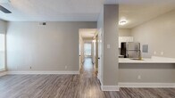 Located at 2003 Skyline Dr in McKinney, TX, this single-story 2-bedroom, 2-bathroom residence offers a clean, modern aesthetic throughout. Wood-style plank flooring runs continuously across the living areas, hallway, and bedrooms, creating a cohesive and low-maintenance foundation. The living room serves as the heart of the home, featuring a tile-surround fireplace, a ceiling fan with light fixture, and a large window with patio door access that fills the space with natural light. Adjacent to the living area, the kitchen is outfitted with white shaker-style cabinetry, a subway tile backsplash, white quartz countertops, stainless steel appliances including a refrigerator, range, and microwave, and a peninsula with an undermount sink — ideal for casual dining or meal prep. A central hallway connects the two bedrooms and bathrooms, maintaining an efficient and private layout. Both bedrooms include ceiling fans, windows with blinds, and neutral walls. The bathrooms are appointed with gray vanity cabinetry, gold hardware accents, white quartz countertops, and tub/shower combinations. Textured ceilings and consistent neutral-toned walls throughout contribute to the home's bright, welcoming ambiance.
