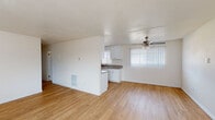 Located at 1810 Plaza del Amo in Torrance, California, this single-floor unit offers a clean, functional layout designed for comfortable everyday living. Warm hardwood-style flooring runs consistently throughout the space, creating a cohesive and inviting atmosphere from room to room.

The open living and dining area is generously proportioned, featuring a ceiling fan and a wall-mounted heater unit. The space flows naturally toward the kitchen pass-through, which provides a sense of openness between the two areas. Vertical blinds on large windows allow abundant natural light to fill the rooms while offering privacy.

The galley-style kitchen is well-appointed with crisp white shaker cabinetry extending to the ceiling on both sides, offering ample storage. Granite-look countertops line both walls, accompanied by a double-basin sink and a stainless steel electric range, making the kitchen both practical and visually appealing.

The bedrooms are bright and comfortably sized, each featuring large windows with vertical blinds that invite natural light. One bedroom includes a built-in sliding-door closet, providing convenient storage. The bathroom is neatly finished with a white vanity, granite-look countertop, an oval sink, and a large mirror, complemented by a window for natural ventilation. The overall aesthetic is clean, bright, and move-in ready.