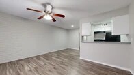 Located at 403 Small Hill Dr in Grand Prairie, Texas, this single-floor unit offers a well-organized layout across three distinct areas. The main living space is a standout, featuring a striking whitewashed brick accent wall that adds texture and character to the room. Wood-look vinyl plank flooring runs throughout, providing a cohesive and easy-to-maintain surface. A ceiling fan with an integrated light fixture centers the living area, ensuring both comfort and illumination. Recessed lighting further brightens the space.

The kitchen is accessed via a passthrough opening from the living area, creating an open and connected feel. It is designed in a galley style, equipped with white cabinetry, gray laminate countertops, and black appliances including a refrigerator and range. Open shelving provides additional storage alongside the cabinetry.

The bathroom features tile flooring, a white vanity with gray countertop, and a full tub and shower combination enclosed in warm-toned tile with a decorative mosaic accent border. The entry area provides a clean and simple transition into the home through a solid white panel door. Overall, the unit presents a clean, neutral palette throughout, making it a versatile and functional living space.