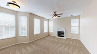 This single-floor home offers a thoughtfully laid-out floor plan with comfortable living spaces throughout. The expansive living room serves as the heart of the home, featuring plush wall-to-wall carpeting, an arched decorative fireplace, a ceiling fan with light fixture, and an abundance of natural light streaming through multiple windows fitted with white blinds. A second carpeted room with sliding door access provides additional flexible living space.

The kitchen is well-appointed with warm honey-toned wood cabinetry offering ample storage, light countertops, and a full suite of black appliances including an electric range, built-in microwave, dishwasher, and a side-by-side refrigerator with ice and water dispenser. A double basin sink with a pass-through view adds to the kitchen's functionality.

The bedrooms are carpeted and bright, each featuring windows that bring in natural light. One bedroom includes access to a walk-in closet, providing generous storage. Two full bathrooms serve the home, each featuring tile flooring, a vanity with dark countertops, and a tub-shower combination. White cabinetry in both bathrooms offers additional storage. Throughout the home, neutral beige tones and a textured ceiling create a warm, cohesive ambiance.