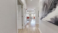 Located in the vibrant Baldwin Park neighborhood of Orlando, Florida, this single-floor unit offers a thoughtfully designed layout that maximizes every square foot. Light hardwood-style flooring flows seamlessly throughout, creating a cohesive and airy feel from entry to living space.

A welcoming hallway leads into the open-concept kitchen and living area, which serves as the heart of the home. The kitchen is well-appointed with rich wood cabinetry, granite countertops, stainless steel appliances — including a full-size refrigerator, range, and microwave — and a central island with pendant lighting overhead, providing both additional prep space and casual seating. Large windows along the kitchen area invite generous natural light.

The living room features vaulted ceilings that enhance the sense of openness, with a glass door offering direct outdoor access and additional natural light. Neutral gray walls provide a clean, modern backdrop throughout the space.

The bathroom is finished with wood-toned cabinetry, a white countertop, a large mirror, and a glass-enclosed shower with tile surround, reflecting a clean, contemporary aesthetic. An in-unit laundry area adds everyday convenience. This efficiently designed space combines modern finishes with functional living in one of Orlando's most walkable communities.