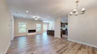 This single-story home in Boonville, Missouri, showcases a clean, contemporary design with neutral tones and modern finishes throughout. The open-concept living and dining area is a standout feature, centered around a sleek linear electric fireplace framed by a crisp white surround. Wide-plank hardwood-style flooring flows seamlessly through the main living spaces, complemented by recessed lighting and a ceiling fan overhead. Multiple windows invite abundant natural light, offering views of the surrounding greenery.

The kitchen is well-appointed with rich, dark-stained cabinetry, granite-style countertops, a large island with a undermount sink, and a full suite of stainless steel appliances including a range, microwave, dishwasher, and refrigerator. The layout connects effortlessly to the main living area, making it ideal for entertaining.

A dedicated laundry room includes washer and dryer units with built-in shelving and light-toned tile flooring. Bedrooms are carpeted for comfort, with one featuring a glass-paneled exterior door providing outdoor access. The bathrooms are finished with dark wood vanities, white countertops, and light tile flooring—one featuring a walk-in shower, the other a tub-shower combination.