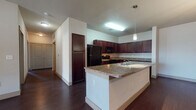 Located at 1201 Albert Ave in Midland, Texas, this single-floor unit offers a thoughtfully designed layout with a cohesive blend of dark wood tones and neutral finishes throughout. The kitchen serves as a central highlight, showcasing rich, dark cabinetry that extends floor to ceiling, granite countertops, and a suite of black appliances including a range, microwave, refrigerator, and dishwasher. A peninsula with a granite surface provides additional prep space and doubles as a casual dining or gathering area. Dark hardwood-style flooring runs through the kitchen and living areas, lending a warm, polished feel. The bedrooms are carpeted and feature ceiling fans, natural light from large windows with blinds, and generous closet space with panel-style doors. The bathrooms are finished consistently with the rest of the unit, featuring dark wood vanities, granite countertops, large mirrors, and tiled tub-shower combinations with hardwood-style flooring. The neutral wall tones throughout create a clean, versatile backdrop. The unit's single-level layout ensures easy accessibility and a seamless flow between living, dining, kitchen, and bedroom spaces.