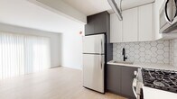 Located in the heart of Hollywood at 1811 Tamarind Ave, this single-floor unit offers a clean, modern aesthetic throughout. Light wood-style flooring runs continuously across the living areas and bedrooms, lending warmth and visual cohesion to the space.

The kitchen is a standout feature, outfitted with two-tone cabinetry — charcoal grey lower cabinets paired with white upper cabinets — and a striking hexagonal white tile backsplash. Stainless steel appliances include a full-size refrigerator, gas range, and built-in microwave, providing a fully functional and stylish cooking environment. A single-basin sink with a matte black faucet completes the kitchen.

The open living area adjoins the kitchen seamlessly, offering a generous, flexible layout bathed in natural light from large windows dressed with vertical blinds. The crisp white walls enhance the brightness of the space and create a clean, neutral canvas.

The bedrooms are well-proportioned, each featuring windows that invite natural light and views of the surrounding neighborhood. The bathroom is fitted with a glass-enclosed shower stall with matte black hardware, reflecting the modern design language carried throughout the unit.

Overall, the space presents a contemporary, move-in-ready feel with consistent finishes and a bright, airy atmosphere well-suited to urban living in Los Angeles.