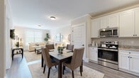 Located at 180 Westfall Town Dr in Matamoras, PA, this single-floor residence offers a thoughtfully designed open-concept layout finished with consistent light hardwood-style flooring and crown molding throughout. Neutral warm tones on the walls create a cohesive, inviting ambiance across all living areas.

The kitchen is well-equipped with white shaker-style cabinetry extending to the ceiling, granite countertops, and a full suite of stainless steel appliances including a range, over-the-range microwave, and a large French door refrigerator. It flows directly into the dining area and living room, making the combined space ideal for everyday living and entertaining. The living room benefits from natural light provided by a large window fitted with blinds.

The primary bedroom is generously sized, featuring a ceiling fan, large window with outdoor views, and ample floor space. The en-suite bathroom includes a granite-topped vanity, a glass-enclosed walk-in shower, and hardwood-style flooring. A second bedroom offers similar natural light and ceiling fan. A dedicated home office provides a quiet, windowed workspace. The in-unit laundry room houses a full-sized washer and dryer with additional shelving.