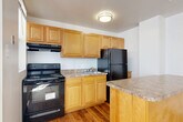 Located at 1436 R St NW in Washington, DC's dynamic U Street neighborhood, this two-bedroom, one-bathroom unit offers a practical and well-organized layout across a single floor. The kitchen is a functional highlight, featuring warm honey-toned wood cabinetry, granite-style countertops, black appliances including a range and full-size refrigerator, and hardwood flooring. A peninsula separates the kitchen from the combined living and dining area, which transitions to soft carpet and is illuminated by a pendant light, creating a comfortable, open feel. The primary bedroom is generously proportioned, with carpet flooring, multiple windows that invite natural light, and access to two closets for ample storage. The second bedroom also features carpet and its own closet, along with a mirrored closet door. Both bedrooms are served by a central hallway. The full bathroom includes a soaking tub with tile surround and a window for natural ventilation. Additional features include four closets throughout, a utility room, and a private balcony. The unit's neutral color palette and clean finishes provide a versatile canvas suited to a variety of lifestyles in one of DC's most walkable and vibrant neighborhoods.
