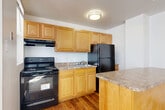 Located at 1436 R St NW in Washington, DC's dynamic U Street neighborhood, this two-bedroom, one-bathroom unit offers a practical and well-organized layout across a single floor. The kitchen is a functional highlight, featuring warm honey-toned wood cabinetry, granite-style countertops, black appliances including a range and full-size refrigerator, and hardwood flooring. A peninsula separates the kitchen from the combined living and dining area, which transitions to soft carpet and is illuminated by a pendant light, creating a comfortable, open feel. The primary bedroom is generously proportioned, with carpet flooring, multiple windows that invite natural light, and access to two closets for ample storage. The second bedroom also features carpet and its own closet, along with a mirrored closet door. Both bedrooms are served by a central hallway. The full bathroom includes a soaking tub with tile surround and a window for natural ventilation. Additional features include four closets throughout, a utility room, and a private balcony. The unit's neutral color palette and clean finishes provide a versatile canvas suited to a variety of lifestyles in one of DC's most walkable and vibrant neighborhoods.