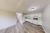 Located at 1850 Squire Dr in Saginaw, Michigan, this 2-bedroom, 1-bathroom single-floor unit offers a practical and functional layout. The open-concept kitchen, dining, and living area forms the heart of the home, finished with durable wood-look flooring throughout. The kitchen is equipped with white cabinetry offering ample storage, a double-basin sink, electric range, refrigerator, and dishwasher, all set in a clean, light-toned L-shaped configuration.

The living area extends toward a full-width sliding glass door that opens to a view of an outdoor green space, bringing in natural light and providing convenient outdoor access. A hallway connects the main living area to the private quarters, where two carpeted bedrooms offer a quieter, softer underfoot feel. Each bedroom includes louvered bi-fold closet doors, and the space is served by three closets in total, providing generous storage throughout the unit. One bedroom features a window with an exterior view, while baseboard heating is present in multiple rooms.

The single full bathroom includes a tub-shower combination, toilet, and a white vanity with storage, finished with wood-look flooring consistent with the rest of the unit. Neutral wall tones and clean white trim carry throughout, giving the space a cohesive, move-in-ready appearance.