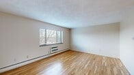 Located at 8 Charlesbank Way in Waltham, MA, this two-bedroom, one-bathroom residence offers a practical and comfortable single-floor layout. Warm hardwood flooring flows consistently throughout the living areas and bedrooms, lending a cohesive and inviting feel to the entire space.

The living room is generously sized, featuring a large window that draws in natural light and provides views of the surrounding neighborhood. A built-in wall unit provides both heating and cooling, ensuring year-round comfort. Textured ceilings add a classic character throughout.

The kitchen is efficiently designed with warm honey-toned wood cabinetry, granite countertops, tile flooring, and a full suite of white appliances including a refrigerator, electric range, over-the-range microwave, and dishwasher. A window above the sink brings in additional natural light.

Both bedrooms are well-proportioned with hardwood floors, neutral walls, and baseboard heating. The primary bedroom is notably spacious, featuring a large window with exterior views. The second bedroom offers similar comfort with a closet and easy access to the hallway.

The bathroom is finished with white tile walls and a decorative tiled floor, featuring a combined tub and shower. A connecting hallway ties all rooms together, contributing to a smooth and functional flow throughout the residence.