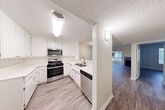 This single-floor residence offers a well-organized layout with a clean, neutral aesthetic throughout. The kitchen is a functional highlight, featuring white cabinetry, light countertops, and a full suite of stainless steel appliances including a gas range, over-the-range microwave, and dishwasher. A pass-through counter connects the kitchen to an adjacent dining or flex area, enhancing the open flow between spaces. Light wood-look flooring runs through the kitchen and transitions to a slightly deeper tone in the main living areas.

The living room is bright and spacious, anchored by a fireplace and a sliding glass door that opens to an outdoor balcony, allowing natural light to fill the space. Crown molding and a textured ceiling add a classic finishing detail throughout the common areas.

The bedroom is a comfortable, well-proportioned room with a window providing natural light and a standard closet with a full-width hanging rod for ample storage. The bathroom includes a full-size soaking tub with a tiled surround and clean white finishes. Overall, the space presents a bright, neutral palette with consistent flooring and trim that creates a cohesive, move-in-ready environment.