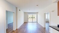 This efficiently designed single-floor unit offers three bedrooms, two full bathrooms, a kitchen, and a dedicated closet, all finished with warm-toned hardwood flooring throughout. The open living area is a standout feature, bathed in natural light from a large sliding glass door that leads to an outdoor patio area. Crisp white walls and clean lines create a bright, airy ambiance across the space.

The kitchen is well-appointed with rich warm-toned cabinetry, dark granite countertops, stainless steel appliances including a gas range, built-in microwave, and refrigerator, complemented by track lighting overhead and a peninsula that provides additional counter space and separation from the living area.

The bedrooms are finished consistently with hardwood floors and white walls, each featuring windows fitted with blinds that allow for natural light control. One bedroom includes a closet. Both bathrooms follow the same design language, featuring warm wood vanities, dark granite countertops, large mirrors, and tub-shower combinations with white tile surrounds and chrome fixtures, maintaining a cohesive and clean aesthetic throughout the unit.