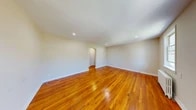 Located at 10 Lloyd Street, Unit 3B in Nutley, NJ, this 2-bedroom, 1-bathroom residence offers a well-organized single-floor layout that makes efficient use of its space. Rich, warm-toned hardwood flooring runs throughout the living areas and bedrooms, adding a classic character to the home. The spacious living room is bright and open, featuring recessed lighting, an arched doorway detail, and a radiator for heating, with natural light streaming in through large windows. An entry hallway welcomes you in with its own window and wood floors, creating a warm first impression. The combined kitchen and dining area is outfitted with warm oak cabinetry, granite-style countertops, a stainless steel sink, and a white gas range, with light vinyl flooring and an arched passageway connecting it to the rest of the home. The dining area includes a stainless refrigerator and a large window with a radiator beneath it, filling the space with natural light. The two bedrooms are well-proportioned, including a generously sized primary bedroom, and together they are served by five closets throughout the unit—providing excellent storage. The full bathroom features a white vanity, a soaking tub with black tile surround, a separate shower, and a window for natural ventilation. The neutral, beige-toned walls throughout create a clean, cohesive aesthetic.