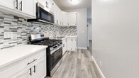 Located at 1032 S Normandie Ave in Los Angeles, this single-story, 3-bedroom, 2-bathroom home has been thoughtfully renovated with modern finishes throughout. Light gray wood-look flooring flows seamlessly across every room, creating a clean and cohesive aesthetic. The kitchen is a standout feature, equipped with stainless steel appliances including a gas range, microwave, and refrigerator, complemented by crisp white cabinetry with matte black hardware and a striking mosaic tile backsplash. The combined dining and living area offers an open, flexible layout. Each bedroom is bright and airy, featuring soft blue-gray walls, ceiling fans, and white-slat window blinds that allow natural light to filter in. The primary bedroom includes a mirrored sliding closet and direct access to an en-suite bathroom. The two bathrooms are well-appointed: one features a glass-enclosed marble-tiled walk-in shower, while the other offers a glass sliding door shower, both with white vanities, mirrored medicine cabinets, and overhead storage. A hallway connects the bedrooms efficiently. The overall ambiance is fresh, clean, and move-in ready, with consistent modern detailing throughout the entire home.