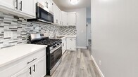 Located at 1032 S Normandie Ave in Los Angeles, this single-story, 3-bedroom, 2-bathroom home has been thoughtfully renovated with modern finishes throughout. Light gray wood-look flooring flows seamlessly across every room, creating a clean and cohesive aesthetic. The kitchen is a standout feature, equipped with stainless steel appliances including a gas range, microwave, and refrigerator, complemented by crisp white cabinetry with matte black hardware and a striking mosaic tile backsplash. The combined dining and living area offers an open, flexible layout. Each bedroom is bright and airy, featuring soft blue-gray walls, ceiling fans, and white-slat window blinds that allow natural light to filter in. The primary bedroom includes a mirrored sliding closet and direct access to an en-suite bathroom. The two bathrooms are well-appointed: one features a glass-enclosed marble-tiled walk-in shower, while the other offers a glass sliding door shower, both with white vanities, mirrored medicine cabinets, and overhead storage. A hallway connects the bedrooms efficiently. The overall ambiance is fresh, clean, and move-in ready, with consistent modern detailing throughout the entire home.