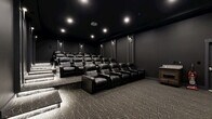 Located at 1125 Old Graves Mill Rd in Lynchburg, Virginia, this private screening room delivers a true cinema experience in a thoughtfully designed, single-level space. The room is finished entirely in deep charcoal and black tones — from the dark ceiling to the matte walls — creating an immersive, distraction-free environment ideal for film viewing.

Multiple rows of plush black leather recliner seats are arranged on a tiered, stadium-style platform layout, ensuring unobstructed sightlines from every position. Each recliner features built-in cup holders, and the seating capacity accommodates a generous number of guests. A large projection screen anchors the front wall, paired with a ceiling-mounted projector for a full cinematic presentation.

The flooring throughout features a patterned geometric carpet in charcoal and grey tones, adding texture while contributing to the room's acoustic qualities. Recessed ceiling lights and wall-mounted sconces provide controlled, dimmable ambient lighting along the side walls, complementing the theatrical ambiance. Step lighting along the tiered platforms ensures safe navigation in low-light conditions.

The space is accessed through a paneled door and is equipped with an emergency exit, reflecting both functionality and safety. A small side cabinet offers convenient storage or service space. Every design detail of this screening room is oriented toward delivering an exceptional, cinema-grade viewing experience.