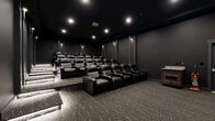 Located at 1125 Old Graves Mill Rd in Lynchburg, Virginia, this private screening room delivers a true cinema experience in a thoughtfully designed, single-level space. The room is finished entirely in deep charcoal and black tones — from the dark ceiling to the matte walls — creating an immersive, distraction-free environment ideal for film viewing.

Multiple rows of plush black leather recliner seats are arranged on a tiered, stadium-style platform layout, ensuring unobstructed sightlines from every position. Each recliner features built-in cup holders, and the seating capacity accommodates a generous number of guests. A large projection screen anchors the front wall, paired with a ceiling-mounted projector for a full cinematic presentation.

The flooring throughout features a patterned geometric carpet in charcoal and grey tones, adding texture while contributing to the room's acoustic qualities. Recessed ceiling lights and wall-mounted sconces provide controlled, dimmable ambient lighting along the side walls, complementing the theatrical ambiance. Step lighting along the tiered platforms ensures safe navigation in low-light conditions.

The space is accessed through a paneled door and is equipped with an emergency exit, reflecting both functionality and safety. A small side cabinet offers convenient storage or service space. Every design detail of this screening room is oriented toward delivering an exceptional, cinema-grade viewing experience.