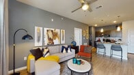 This single-story residence is thoughtfully designed with a contemporary aesthetic, blending bold accent colors with clean, modern finishes. The open-concept living area features elevated ceilings with a ceiling fan, bold slate-gray accent walls, and light wood-style flooring that flows seamlessly into the kitchen. Large windows allow natural light to fill the space, enhancing its welcoming atmosphere.

The galley-style kitchen is well-appointed with dark wood cabinetry, granite countertops, a full suite of stainless steel appliances including a refrigerator, range, microwave, and dishwasher, as well as a tiled backsplash and pendant lighting that adds a stylish touch.

Two bedrooms offer carpeted floors, ceiling fans, and windows fitted with blinds and curtains. Each room provides a comfortable, private retreat with ample space for furnishings.

Two full bathrooms mirror the kitchen's design language, featuring dark wood vanities with granite countertops, wood-style flooring, and tub-shower combinations with tasteful tilework.

Additional highlights include a generously sized walk-in closet with built-in wire shelving, providing practical and efficient storage for the entire unit.