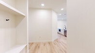This well-designed single-story home in Round Rock, Texas offers three bedrooms and three bathrooms within a clean, modern aesthetic. Light wood-tone flooring runs throughout, complementing the crisp white walls and recessed lighting that keep the interior bright and airy.

The open-concept kitchen and living area serves as the heart of the home. The kitchen is outfitted with sleek white cabinetry, a large center island with an undermount sink, marble-style backsplash, a stainless steel refrigerator, and a wall-mounted range hood — all contributing to a polished, contemporary feel. Built-in shelving and a desk area provide additional functional workspace nearby.

The living area is generously sized, featuring large windows and a glass door that invite natural light and offer outdoor views. Each bedroom is comfortably proportioned, with large windows fitted with blinds, light flooring, and ceiling fans for added comfort. Closets include built-in shelving and double doors with matte black hardware. The bathrooms are finished with white cabinetry, LED-lit mirrors, undermount sinks, matte black fixtures, and tiled tub-shower combinations. A dedicated laundry room includes a full-size washer and dryer. The home presents a cohesive, move-in-ready environment with consistent modern detailing throughout.