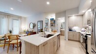 Located at 7910 South New Braunfels Avenue in San Antonio, TX, this single-story 2-bedroom, 2-bathroom home offers a thoughtfully designed open-concept layout with modern finishes throughout. Light wood-tone flooring flows seamlessly across the entire space, complementing the clean white walls and creating a bright, cohesive aesthetic.

The kitchen serves as a central hub, featuring light wood cabinetry extending to the ceiling, white quartz countertops, stainless steel GE appliances including a range, microwave, and French door refrigerator, and a kitchen island with bar seating and an integrated sink — ideal for both cooking and casual dining.

The open living and dining area is bathed in natural light from large windows dressed with sheer curtains and gold curtain rods. The living room offers generous space for relaxing and entertaining.

Both bedrooms are well-proportioned and bright. The primary bedroom features multiple windows and a dedicated bathroom with a double-sink vanity finished in light wood, white quartz countertops, a large mirror, and a walk-in glass shower. The secondary bedroom also benefits from natural light and is served by a second full bathroom with matching finishes. Two closets provide ample storage throughout the home.