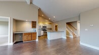 Located at 646 Championship Dr in Victor, NY, this two-story home offers four bedrooms, three bathrooms, and a thoughtfully designed layout spread across two floors. The expansive main floor features a dramatic open-concept living and kitchen area highlighted by soaring vaulted ceilings and recessed lighting. The kitchen is equipped with stainless steel appliances including a refrigerator, range, and microwave, complemented by white shaker cabinetry, granite countertops, and a peninsula island. Warm hardwood-style flooring flows throughout the main living areas, while a staircase with wood balusters leads to the upper level. A dining area features vaulted ceilings and an elegant chandelier. The generously sized primary bedroom is carpeted and filled with natural light. Additional bedrooms are also carpeted and offer outdoor views through large windows. The bathrooms are well-appointed, with one featuring tile surround, a walk-in shower with glass doors, white cabinetry, and crown molding. A second bathroom includes a tub/shower combo. The home also includes a dedicated laundry room with tile flooring and crown molding detailing, a closet, and two hallways connecting the functional layout of this comfortable Victor, NY residence.