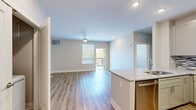 Located at 273–299 E 25th Ave in North Kansas City, MO, this well-appointed one-bedroom, one-bathroom residence offers a thoughtfully designed single-floor layout with modern finishes throughout. The open-concept living and dining area features light-toned hardwood-style flooring, a ceiling fan, recessed lighting, and a sliding door that leads to a private balcony with outdoor views, allowing natural light to fill the space. The kitchen is a standout feature, boasting crisp white shaker cabinetry, granite countertops, a mosaic tile backsplash, stainless steel appliances including a refrigerator, range, and microwave, and a peninsula with an undermount sink — ideal for both cooking and casual dining. The bedroom is carpeted for comfort, fitted with a ceiling fan, and offers a large window framing natural views. It connects to a generously sized walk-in closet outfitted with multi-level wire shelving for ample storage. The full bathroom features wood-style flooring, a granite-topped dual vanity with taupe cabinetry, a large mirror, and a full soaking tub with shower. Neutral tones and clean lines create a cohesive, contemporary ambiance throughout the entire residence.