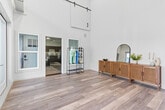 Located at 2315 South 11th Avenue in Bozeman, MT, this one-bedroom, one-bathroom unit offers a well-designed single-floor layout with a variety of impressive architectural details. The entrance immediately sets the tone with dramatic floor-to-ceiling glass doors that flood the space with natural light and soaring double-height ceilings that create an airy, open atmosphere. Light wood-style flooring runs throughout the main living areas, complementing the bright, neutral palette.

The open-concept area seamlessly connects the living room, dining space, and kitchen. The living room features large windows for additional natural light, while the kitchen is outfitted with rich dark cabinetry, granite-style countertops, and a full suite of stainless steel appliances including a refrigerator, range, microwave, and dishwasher. Track lighting enhances the kitchen's functionality.

The spacious bedroom is finished with plush carpet, a window for natural light, and direct access to a dedicated closet. The bathroom features a dark vanity with granite-style countertops, a single undermount sink, and a well-lit mirror. Additional conveniences include an in-unit laundry room. A sliding barn door accent adds a modern-rustic design touch to the main living area.