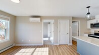 Located at 231 Scarborough Downs Rd in Scarborough, Maine, this well-designed one-bedroom, one-bathroom unit offers a smart and functional single-floor layout. The open-concept living and kitchen area is anchored by a standout kitchen featuring white shaker cabinets, granite countertops, a center island with pendant lighting, and a full suite of stainless steel appliances including a range, microwave, dishwasher, and refrigerator. Light wood-tone luxury vinyl plank flooring runs throughout the main living areas, complementing the neutral warm-gray wall tones and bright white trim. A wall-mounted mini-split unit provides efficient climate control in the living space, which also benefits from natural light. The bedroom is carpeted for comfort, includes a closet, a baseboard heating unit, and a window with outdoor views. The bathroom is clean and functional, finished with LVP flooring, a white vanity, and a tub-shower combination. The overall aesthetic is fresh and modern, with consistent finishes throughout that give the space a cohesive, move-in-ready feel.