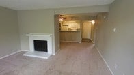 Located at 811 NE Green Oaks in Arlington, Texas, this single-floor residence offers a comfortable and functional layout designed for everyday living. The main living area is carpeted and anchored by a classic white-brick fireplace with a black metal door surround, serving as a warm focal point in the room. The space flows openly into the kitchen and dining area, creating a connected feel throughout. The kitchen features white cabinetry, a built-in microwave, and a bar-height counter that separates it from the main living space, offering a casual spot for dining or conversation. A ceiling fan is centrally positioned to keep the space comfortable year-round. Neutral wall tones and light-toned carpet carry consistently throughout, contributing to a clean and cohesive aesthetic. The entryway, visible from the living area, is well-lit and provides a welcoming transition into the home. The open sightlines between the living room, kitchen, and entryway enhance the sense of space and make the layout feel intuitive and easy to navigate. Overall, the residence presents a straightforward and livable floor plan in a convenient Arlington location.
