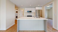 Located at 2453 Renfrew Street in Vancouver, BC, this well-appointed 3-bedroom, 2-bathroom unit is thoughtfully laid out across a single floor. Light hardwood flooring runs throughout, complementing the warm, neutral palette of cream-toned walls that create a clean and airy ambiance.

The modern kitchen is a standout feature, offering sleek white cabinetry, marble-look quartz countertops, stainless steel appliances including a built-in dishwasher and refrigerator, a stainless range hood, and a large island with an integrated sink — ideal for both cooking and entertaining. An in-unit stacked washer and dryer is conveniently located just off the kitchen area.

The primary bedroom provides a comfortable and private retreat, while the two additional bedrooms are versatile spaces suited for family, guests, or a home office. One bedroom features a large built-in closet and a window offering outdoor views. Natural light filters into the bedrooms generously through well-placed windows.

Both bathrooms are finished to a high standard. One features marble-look tile flooring, a glass-enclosed tub and shower combination, while the second boasts a wide marble quartz vanity with black hardware accents and a large mirror. A dedicated hallway and closet complete the functional layout of this bright, contemporary home.
