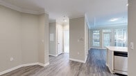 Located at 3421 Northlake Parkway NE in Atlanta, GA, this single-floor unit offers a thoughtfully designed layout that maximizes every square foot. The open-concept kitchen and living area serves as the heart of the space, where the kitchen stands out with crisp white shaker cabinets, light quartz countertops, a tile backsplash, stainless steel appliances including a range, microwave, and refrigerator, and a black undermount sink. The living area is bathed in natural light through large windows and a glass door that opens to a private balcony, framed by elegant crown molding and a tray ceiling. Hardwood-style flooring flows throughout the main living areas, lending warmth and continuity. A dedicated closet area off the living room features built-in shelving, providing practical storage solutions. The bedroom is carpeted for comfort and includes a walk-in closet with built-in shelving, as well as a large window overlooking greenery. A dedicated laundry area with washer/dryer hookups and overhead shelving adds everyday convenience. Neutral warm-gray tones throughout the unit create a clean, cohesive aesthetic well-suited for comfortable living in the Northlake area of Atlanta.