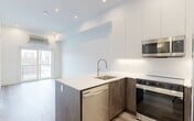 Located at 10125 114 Street NW in Edmonton, this efficiently designed one-bedroom, one-bathroom unit offers a modern and contemporary living experience across a single floor. The open-concept kitchen serves as the centerpiece of the main living area, featuring a peninsula with a quartz countertop, an undermount sink with a pull-down faucet, and a full suite of stainless steel appliances including a refrigerator, electric range, built-in microwave, and dishwasher. Cabinetry combines sleek white upper panels with warm wood-toned lower units, striking a clean and stylish contrast. Recessed lighting throughout enhances the bright, airy ambiance. Light-toned hardwood flooring flows continuously throughout the living spaces, complementing the crisp white walls. The bedroom is a comfortable and quiet retreat, featuring a large window with views of the surrounding neighborhood, allowing natural light to fill the room. A dedicated closet provides organized storage. The bathroom is finished with marble-style tile flooring, a full bathtub with shower, toilet, and a wood-accented vanity, all within a clean, white-dominated palette. A wall-mounted climate control unit and a private entrance door round out the functional features of this well-appointed urban residence.