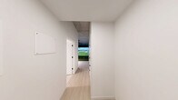Located at 222 Third St in Detroit, MI, this single-floor recreational suite is purpose-built around an indoor golf simulator experience. The centerpiece of the space is a full-size golf simulator bay, complete with artificial turf flooring, a large high-definition projection screen, and a ceiling-mounted projector that delivers immersive, photorealistic course visuals. Dark wall paneling frames the simulator enclosure, creating a focused, stadium-like atmosphere within the bay. A wall-mounted flat-screen TV and a high-top table with stools provide a social viewing area alongside the simulator, making the space suitable for both practice and entertainment. Exposed concrete ceilings and visible ductwork lend the suite an industrial aesthetic throughout. The hallway connects the main simulator area to the supporting amenities, which include a kitchenette with white cabinetry and a full-size stainless steel refrigerator. The bathroom is finished in a clean, contemporary style, featuring large-format tile flooring, a glass-enclosed walk-in shower with white subway tile, a single vanity with matte black fixtures, a framed mirror, and a toilet — all set against crisp white walls. Together, these features make this suite a well-appointed, self-contained facility ideal for golf enthusiasts.