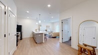 Located at 15 Ore Bank Road in Dillsburg, PA, this single-floor residence offers a thoughtfully designed 2-bedroom, 2-bathroom layout that balances comfort and functionality. The open-concept kitchen and living area serves as the heart of the home, featuring light hardwood-style flooring, recessed lighting, and a seamless flow between spaces. The kitchen is outfitted with gray shaker-style cabinetry, white quartz countertops, stainless steel appliances, and a peninsula island with pendant lighting overhead — ideal for both cooking and casual dining. The living room extends naturally from the kitchen and includes a sliding glass door that fills the space with natural light and provides outdoor views. The generously sized primary bedroom features plush carpeting, a window for natural light, a walk-in closet, and a private en-suite bathroom. The second bedroom also offers comfortable proportions and carpeted flooring. Both bathrooms are finished with gray vanities, white countertops, and hardwood-style tile flooring. A hallway with additional closet storage connects the private quarters to the main living areas. Clean white walls, black hardware accents, and consistent finishes throughout create a cohesive, modern aesthetic across the entire residence.