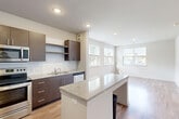 This well-designed one-bedroom, one-bathroom residence in Brandywine, MD offers a thoughtful layout across a single floor. A welcoming entrance hall with wood-style flooring leads into the heart of the home — a bright, open-concept space combining the kitchen, dining, and living areas. The kitchen is a standout feature, showcasing rich dark wood cabinetry extending to ceiling height, a classic white subway tile backsplash, granite countertops, a center island with seating, and a full suite of stainless steel appliances including a refrigerator, electric range, built-in microwave, and dishwasher. Recessed lighting illuminates the space, which flows naturally into the living and dining area. Large windows allow generous natural light and outdoor views of the surrounding neighborhood. The bedroom is a comfortable retreat with its own window, wood-style flooring, and access to ample built-in closet storage with dedicated shelving and hanging rods. The bathroom features a granite-topped vanity with dark cabinetry, a full tub and shower, and an adjacent linen closet. Additional highlights include in-unit laundry and a total of three closets throughout, providing excellent storage for everyday living.