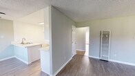 This single-story, 3-bedroom, 2-bathroom home offers a practical and comfortable layout with modern updates throughout. The open-concept living and dining area is bright and inviting, featuring wood-look vinyl flooring, neutral gray walls, a textured ceiling, and a ceiling fan. Large windows along the front of the living room allow generous natural light and views of the outdoor greenery, while a sliding glass door in one of the bedrooms provides additional outdoor access and light.

The kitchen is efficiently designed with white cabinetry, light quartz countertops, a double stainless steel sink set into a peninsula, stainless steel gas range, and a built-in microwave — all illuminated by a flush-mounted ceiling light. The peninsula layout allows for easy interaction with adjacent living spaces.

The three bedrooms are well-proportioned, each featuring the same wood-look flooring and neutral tones. The primary bedroom offers a comfortable footprint with a closet nearby. The two bathrooms are clean and functional, with one featuring a sliding-door shower enclosure, light quartz vanity countertop, and updated fixtures. A dedicated hallway connects the bedrooms and bathrooms, and an additional closet provides useful storage.