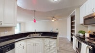 Located at 780 Oak Grove Rd in Concord, California, this single-floor residence offers a well-organized layout with a blend of functional design and comfortable living spaces throughout. The kitchen serves as a central highlight, featuring a curved peninsula with dark countertops, crisp white cabinetry, stainless steel appliances, and a distinctive red pendant light that adds a pop of color. Open to the main living area, the kitchen flows seamlessly into a spacious common area finished with light wood-style flooring and crown molding. A ceiling fan overhead enhances the airy feel, while a built-in shelving unit provides convenient storage. The living area opens directly to a private balcony through sliding glass doors, allowing natural light to fill the room and offering outdoor views of surrounding greenery. The bedrooms are carpeted and generously proportioned, each featuring crown molding, natural light from windows with blinds, and closet space. The bathrooms are clean and functional, with one featuring a full tub-shower combination, white cabinetry with a warm countertop, and wood-style flooring. Throughout the residence, textured ceilings and neutral warm-toned walls create a cohesive and inviting atmosphere.