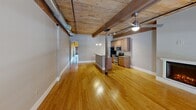 This 1,120 square foot apartment in Manchester, NH offers a perfect blend of industrial charm and modern comfort. The open-concept living area showcases exposed brick walls and wooden ceiling beams, creating a loft-like atmosphere. The kitchen boasts granite countertops, stainless steel appliances, and ample cabinet space. A cozy electric fireplace adds warmth to the living room, which features large windows allowing natural light to flood the space. The primary bedroom, measuring 240 square feet, provides a generous retreat. The bathroom combines functionality with style, featuring a full-size washer and dryer for added convenience. Hardwood floors run throughout the main living areas, while plush carpeting adds comfort to the bedrooms. The apartment's layout includes two hallways, ensuring easy navigation between rooms. With its unique architectural elements and thoughtful design, this apartment offers a distinctive urban living experience in the heart of Manchester.